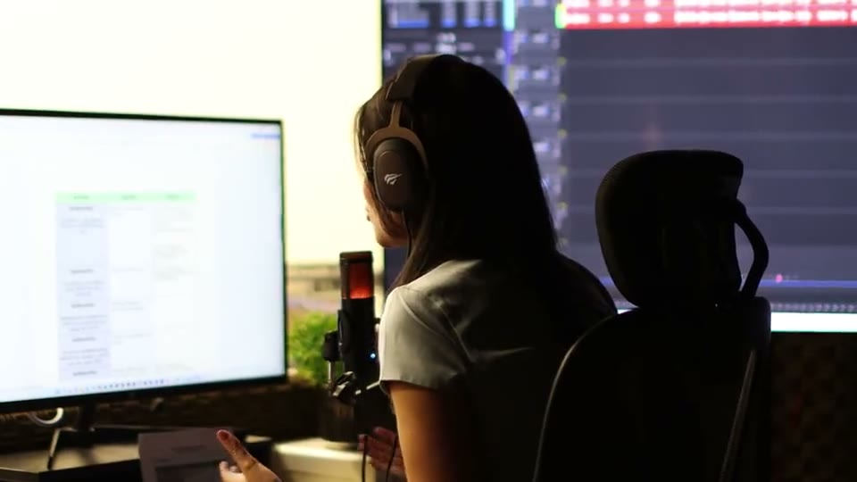 Creator wearing headphones reviewing long-form footage at a computer before cutting it into YouTube Shorts