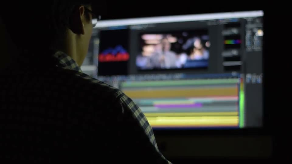 Editor working across dual monitors on a video editing and audio mixing workstation